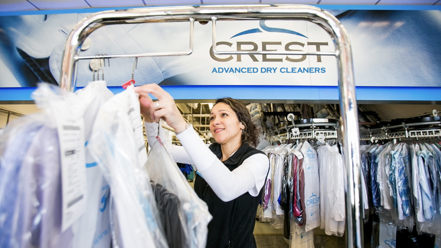 Woman hanging dry cleaning in Crest Advanced Dry Cleaners location