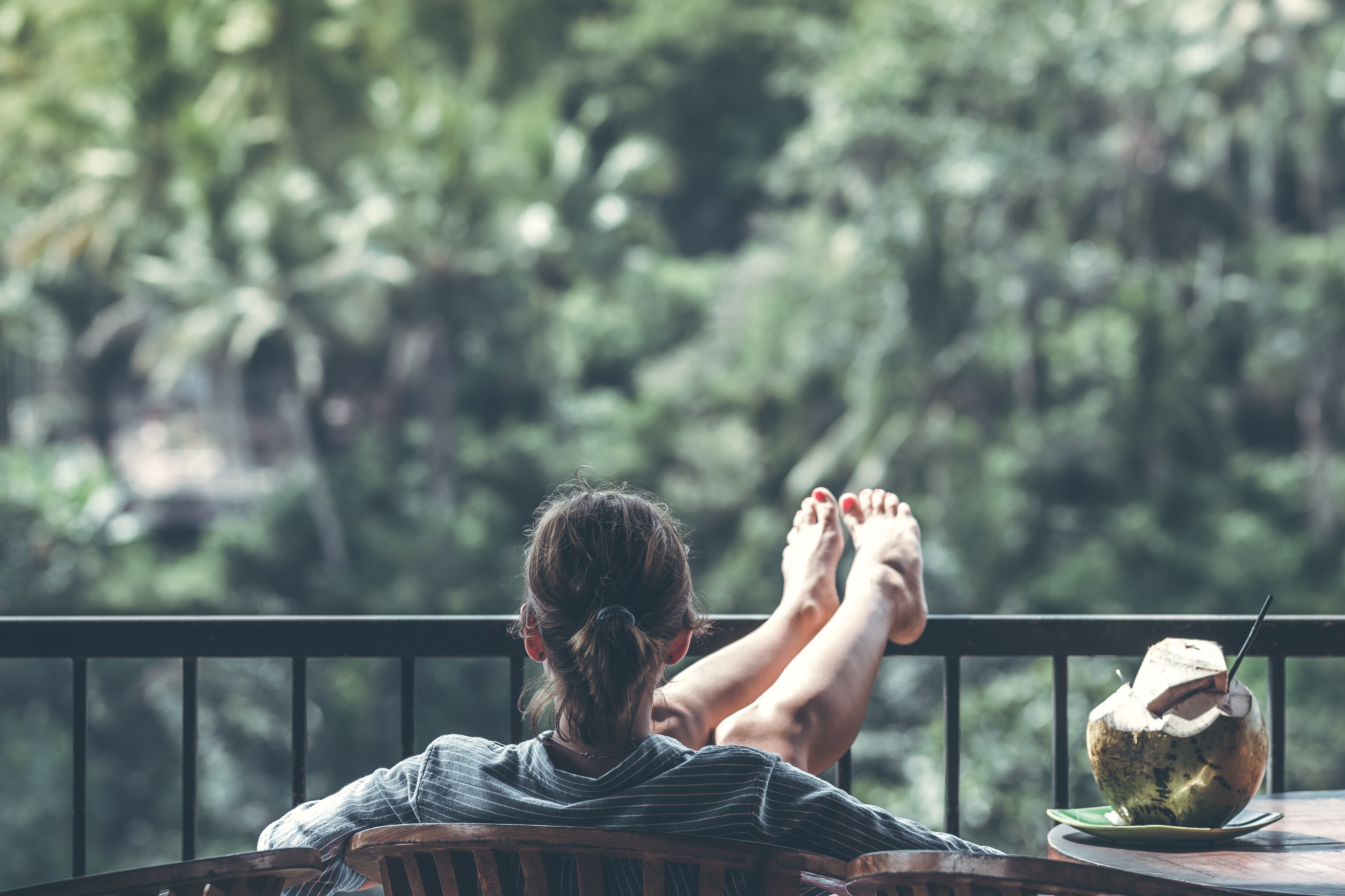 woman relaxes on a balcony with a coconut drink