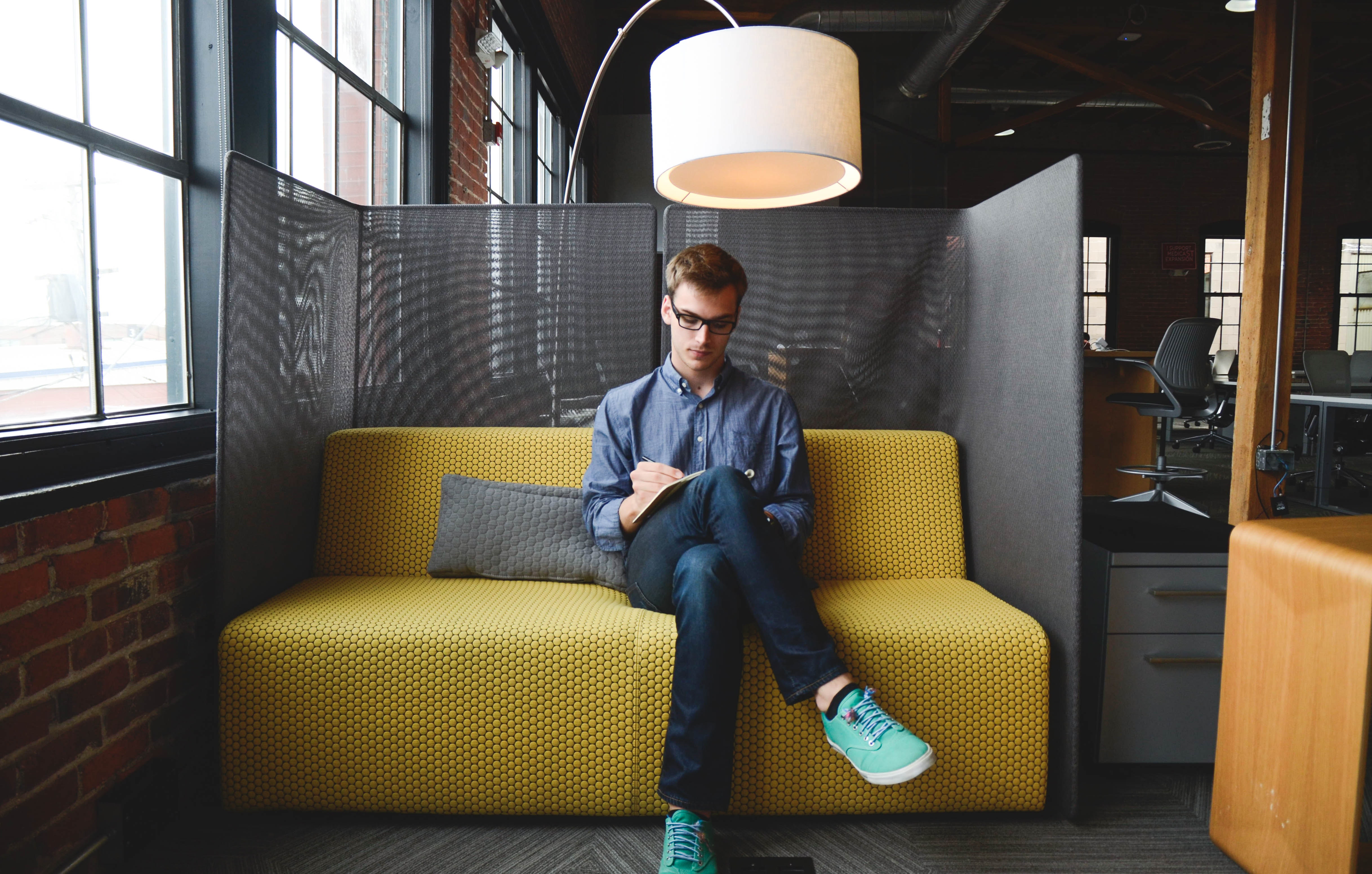 Man sit on yellow couch, reviewing materials