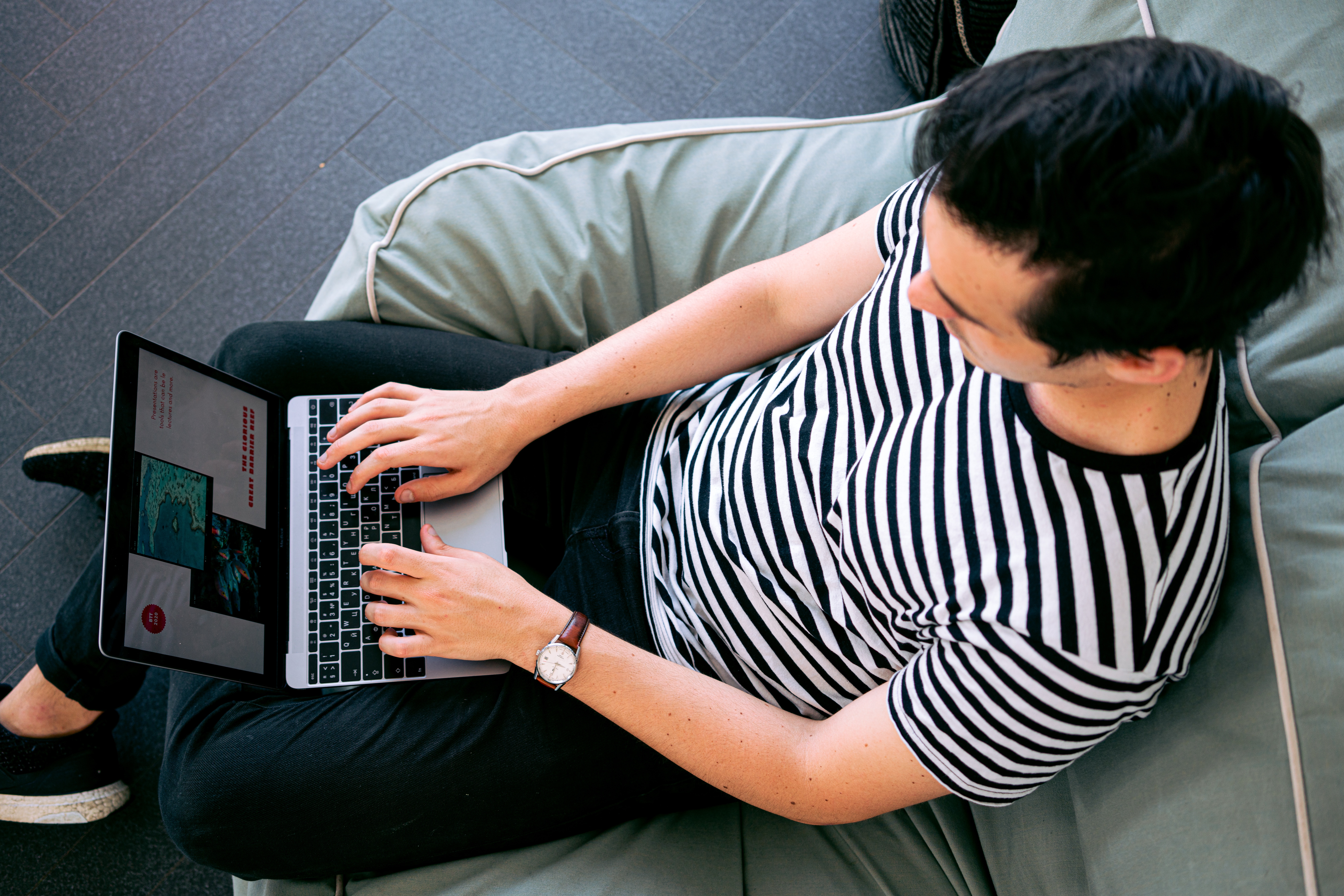 Top down view of a man in a black and white shirt using a laptop