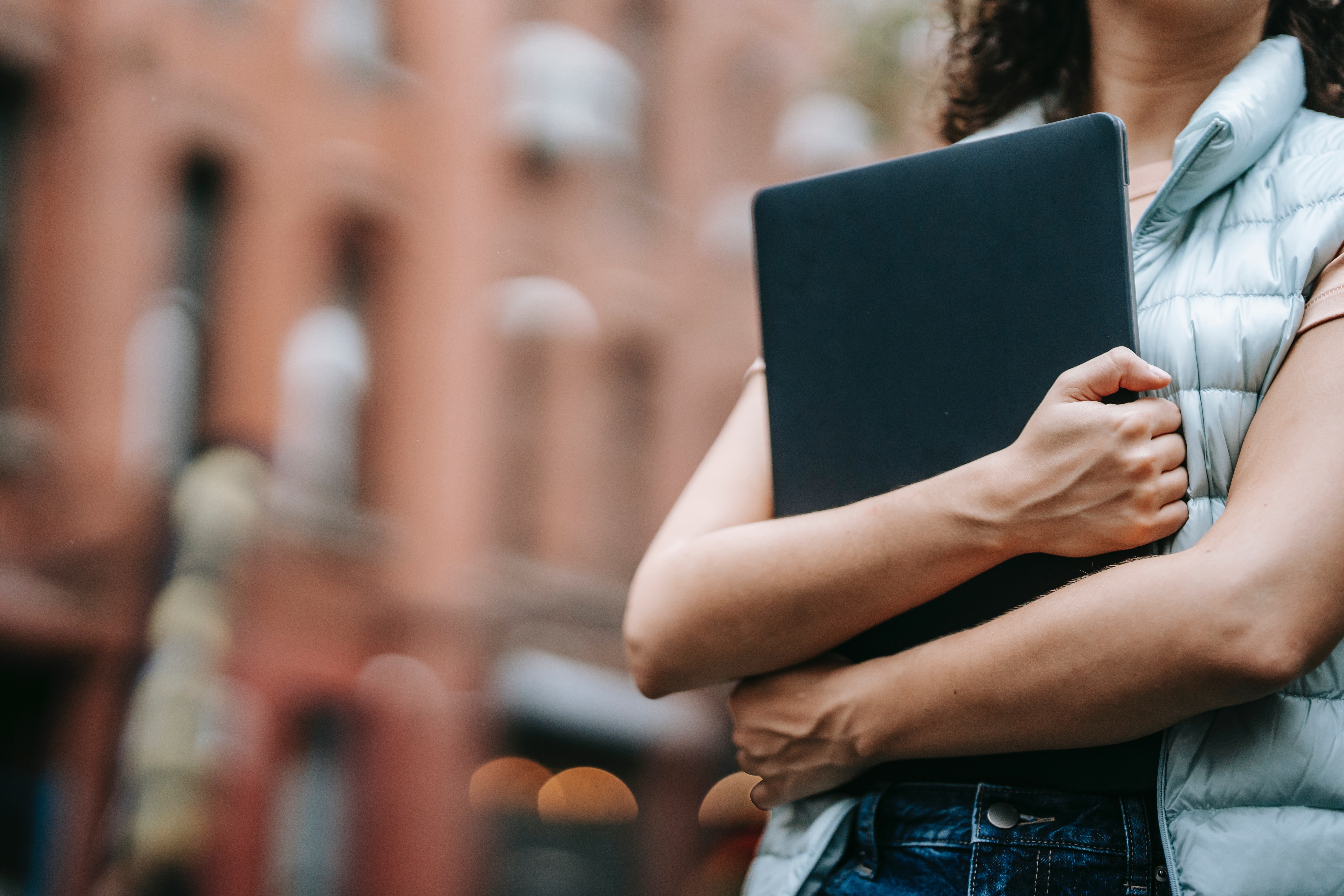 Faceless person holds laptop to chest