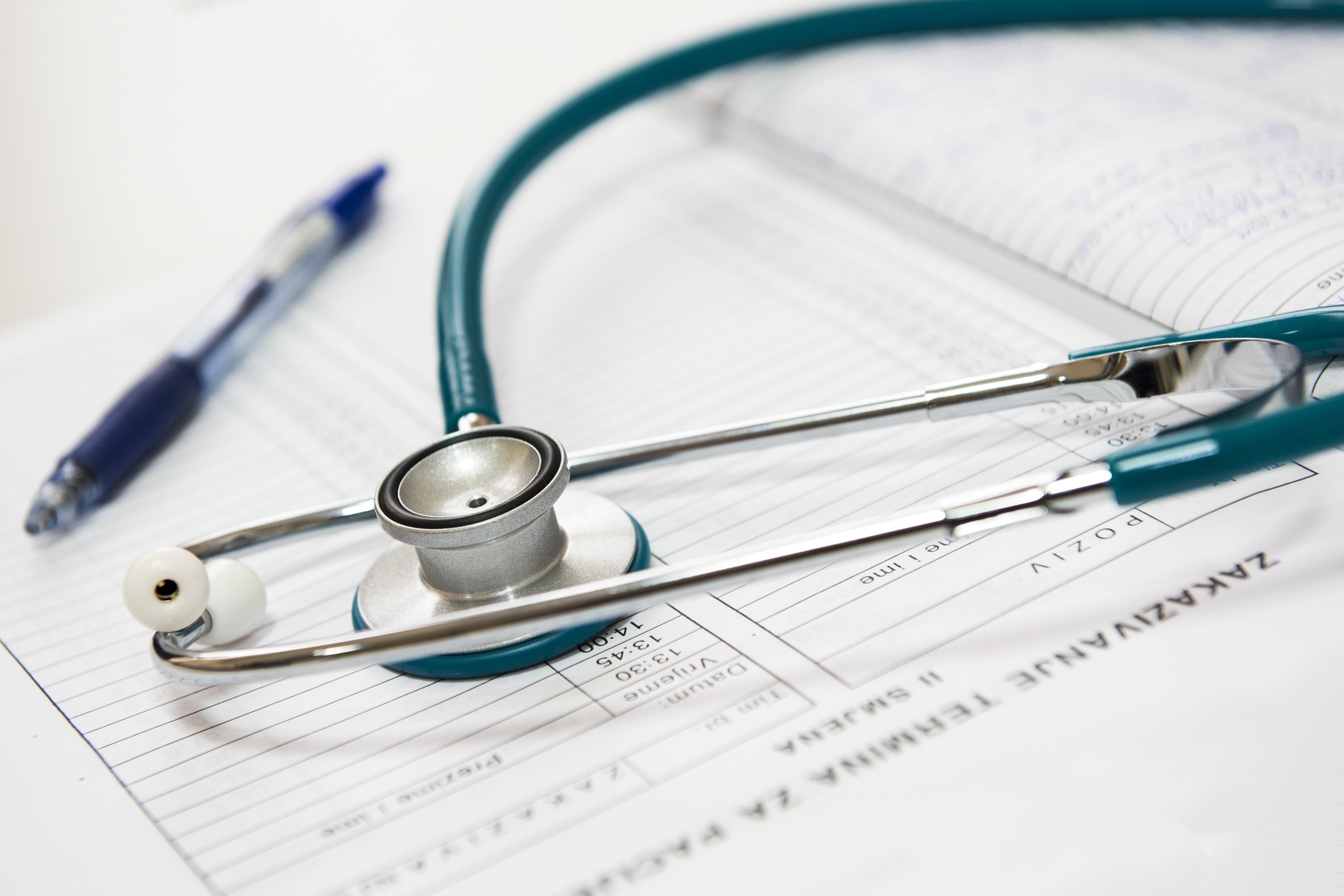 Close up shot of a green and silver stethoscope on a doctor's note pad