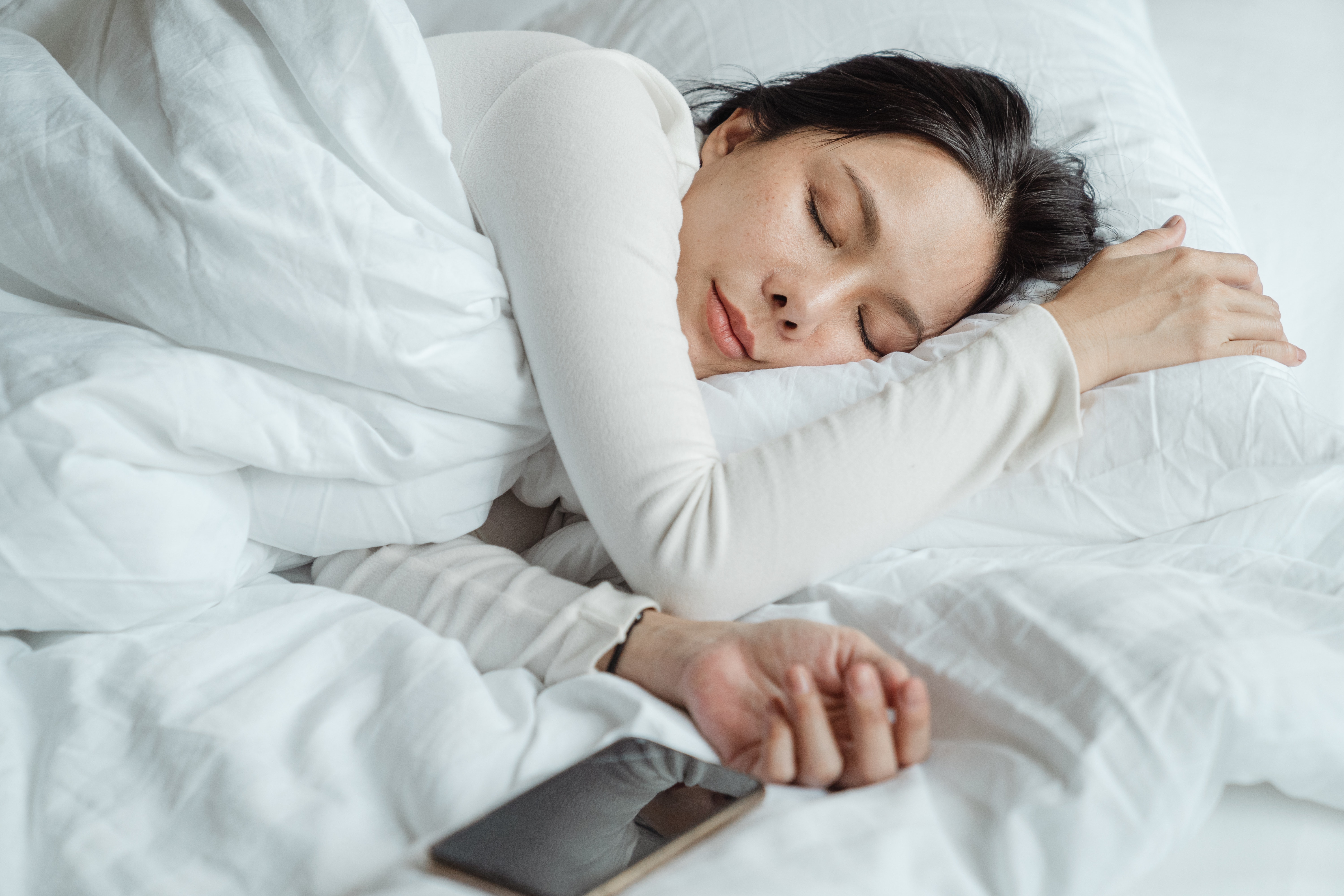 Dark hair woman sleeping with her mobile phone nearby
