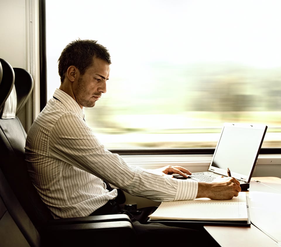Business man works on laptop on train
