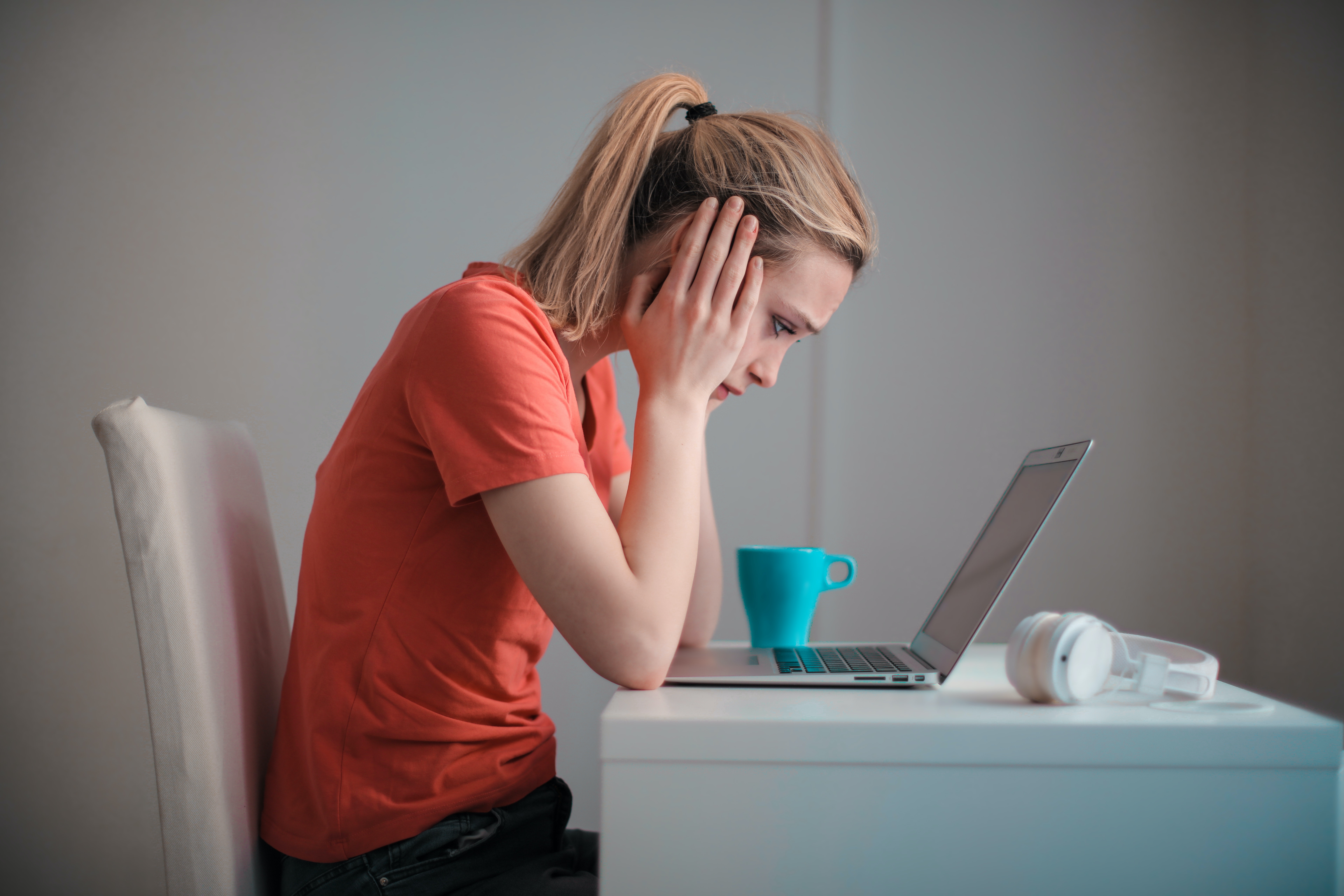 Woman looks worriedly at her laptop, wondering if her business website is sick and who can help her fix it