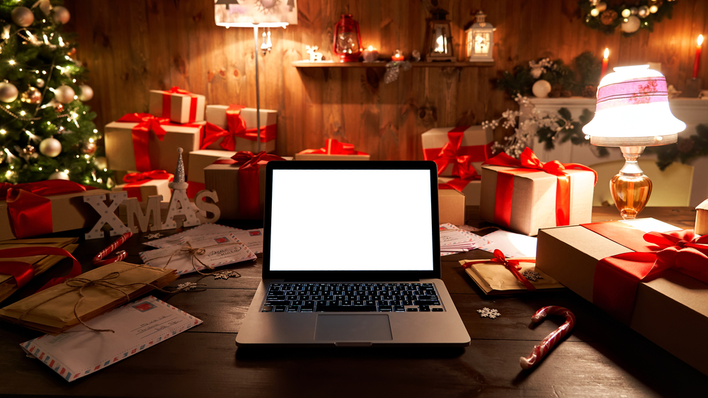 A computer surrounded by christmas decor and new years lighting and a blank computer screen ready to be redesigned