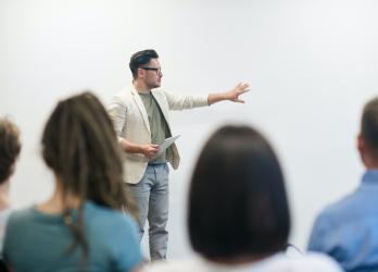 Man in blazer instructs university classroom