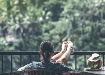 woman relaxes on a balcony with a coconut drink