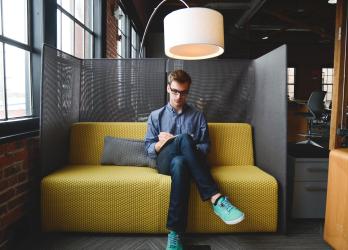 Man sit on yellow couch, reviewing materials