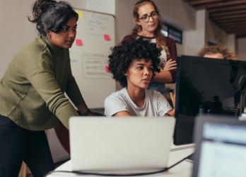 Group of web developers gather around a computer