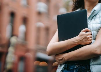 Faceless person holds laptop to chest