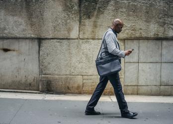 Busy black manager looks at mobile phone