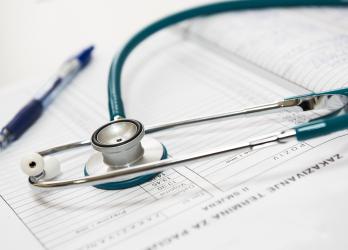 Close up shot of a green and silver stethoscope on a doctor's note pad