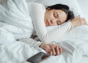 Dark hair woman sleeping with her mobile phone nearby