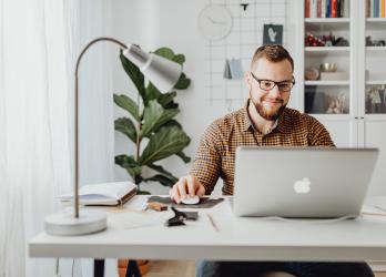 Man sits at his desk and works on his laptop 