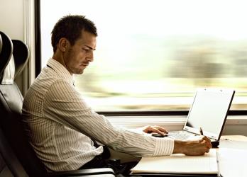 Business man works on laptop on train