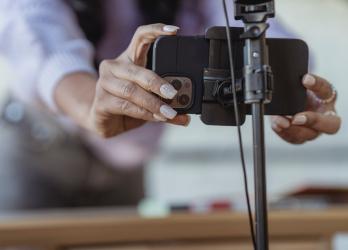 Close up of woman snapping smart phone into a tripod clamp before filming a video