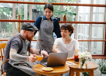 Small business owners crowd around a laptop to read reviews left by customers