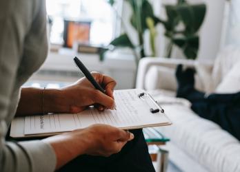 out of frame therapist write advice down on a clipboard for faceless patient 