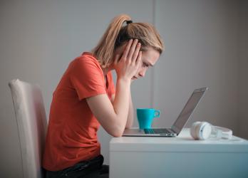 Woman looks worriedly at her laptop, wondering if her business website is sick and who can help her fix it