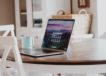 Apple Mac laptop sits open to google on a kitchen table