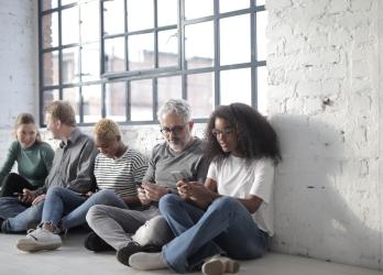 Diverse group of people engage with each other and their mobile phones