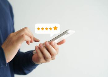 Model holding a smartphone and typing a review with a 5 star review bubble popping out of the phone