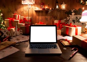 A computer surrounded by christmas decor and new years lighting and a blank computer screen ready to be redesigned