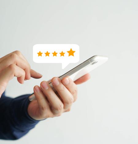 Model holding a smartphone and typing a review with a 5 star review bubble popping out of the phone